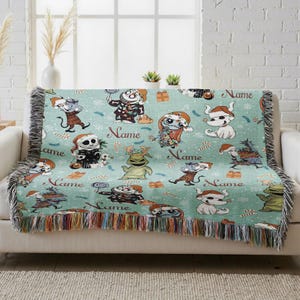 A colorful throw blanket with various cartoon characters and the word "Name" printed on it, placed on a couch in front of a window.