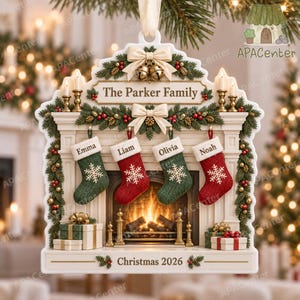 May include: A decorative Christmas ornament shaped like a fireplace mantel with the text The Parker Family and Christmas 2026. It features four hanging stockings labeled Emma, Liam, Olivia, and Noah, decorated with pine garlands, bows, and gifts.