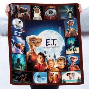 May include: A brown-bordered blanket featuring a collage of images from the movie "E.T. the Extra-Terrestrial." The design includes the film's title, characters, and iconic scenes, set against a backdrop of a full moon and starry night.