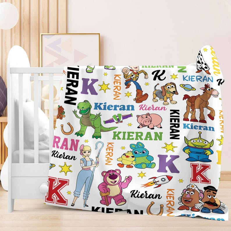 a colorful and playful baby blanket with various cartoon characters and names, such as Kieran, Teddy, and Buzz Lightyear, printed on it.
