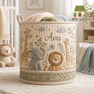 Puede incluir: Una cesta de almacenamiento cilíndrica de tela acolchada color crema con ilustraciones bordadas de una jirafa, un elefante y un león. El nombre Ava está cosido en letra cursiva sobre los animales, rodeado de nubes y motivos vegetales.