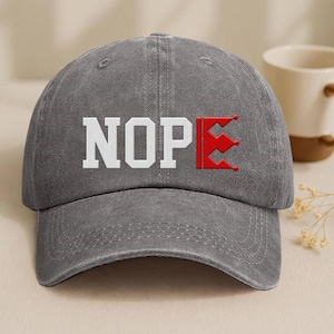 A gray baseball cap with the word "NOPE" printed on it, along with a red flag-like symbol.