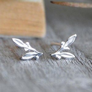 May include: A pair of silver earrings shaped like small sprigs of leaves.