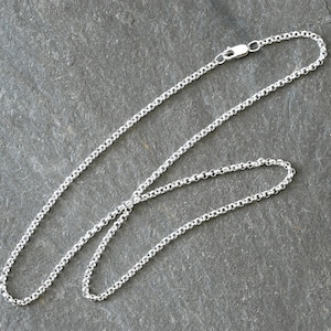 May include: A silver-coloured metal chain necklace featuring a series of interconnected round links. The chain is constructed with a classic rolo link design and includes a small, secure lobster claw clasp mechanism at one end for fastening.