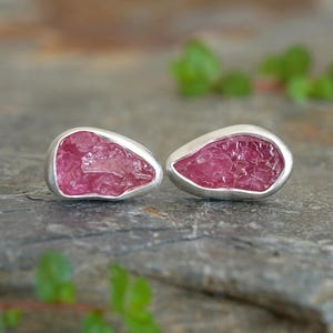 Puede incluir: Un par de pendientes de plata con piedras rosas crudas de tipo cristal en el centro.