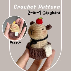 May include: A crocheted capybara figurine with a red fruit on its head, a black scarf, and a brown base. The image includes the text "Crochet Pattern 2-in-1 Capybara" and "Brooch".