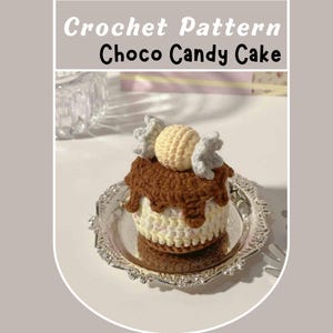 Puede incluir: Un Choco Candy Cake tejido a ganchillo, con un diseño en capas, una cobertura marrón similar al chocolate y un acento de caramelo amarillo. El pastel está presentado en un plato plateado y ornamentado. El texto "Crochet Pattern Choco Candy Cake" se muestra en la parte superior.