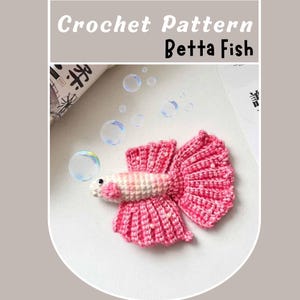 Op de afbeelding: Een haakpatroon voor een roze betta-vis met witte accenten. De vis is omringd door bubbels.