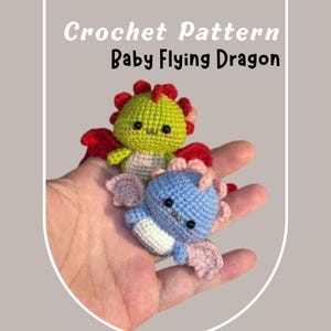 Puede incluir: Dos dragones voladores de bebé tejidos a crochet. Uno es verde con alas rojas y el otro es azul con alas rosas.