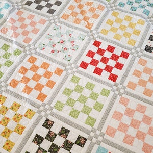 May include: A patchwork quilt with a checkerboard pattern in various colors, including pink, green, yellow, red, and blue. The quilt is made of squares with a white background and a checkerboard pattern in different colors.