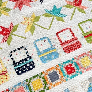 Pode incluir: Um edredom branco com uma variedade de desenhos de patchwork coloridos. O edredom apresenta um padrão repetitivo de estrelas, cestas e quadrados. O edredom é feito com uma variedade de tecidos, incluindo estampas florais, bolinhas e listras.