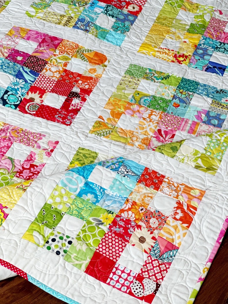 May include: A colorful patchwork quilt with a white background and a quilted pattern of swirls. The quilt is made up of squares of different fabrics in a variety of colors, including red, pink, orange, yellow, green, blue, and purple.