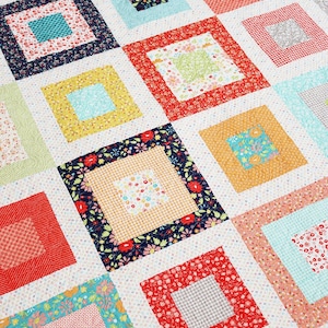 May include: A quilt with a patchwork design featuring squares of various floral prints and colors, including red, yellow, blue, green, and pink. The squares are arranged in a grid pattern, creating a visually appealing and intricate design.