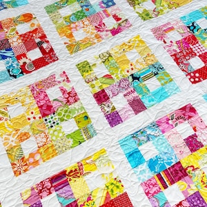May include: A colorful patchwork quilt with a white background and a quilted pattern. The quilt is made up of squares of different fabrics, each with a different pattern. The quilt is a vibrant and cheerful piece of home decor.