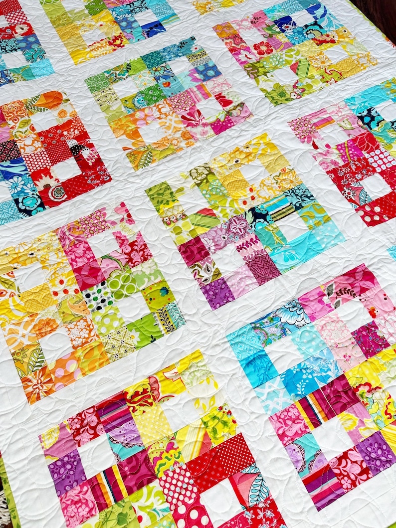 May include: A colorful patchwork quilt with a white background and a quilted pattern. The quilt is made up of squares of different fabrics, each with a different pattern. The quilt is a vibrant and cheerful piece of home decor.