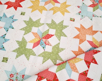 May include: A quilt with a patchwork design featuring a variety of colors and patterns, including green, blue, red, and yellow. The quilt is made up of a series of star-shaped blocks.