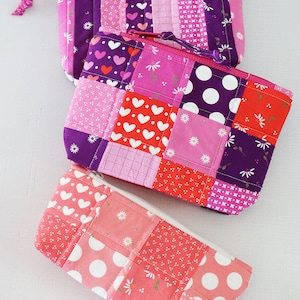 May include: Three patchwork zippered pouches in various shades of pink and purple with white hearts and polka dots.