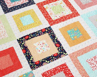 Puede incluir: Una colcha con un diseño de patchwork que presenta cuadrados de varios estampados florales y colores, incluyendo rojo, amarillo, azul, verde y rosa. Los cuadrados están dispuestos en un patrón de cuadrícula, creando un diseño visualmente atractivo e intrincado.