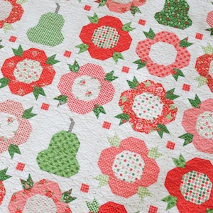 Puede incluir: Un edredón blanco con un patrón repetido de flores rojas y rosas y peras verdes. Las flores tienen centros estampados y hojas verdes. Las peras son verdes con un patrón de cuadros. El edredón está acolchado a máquina.
