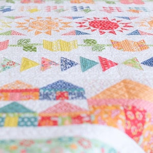 May include: A colorful patchwork quilt with a white background. The quilt features a variety of geometric shapes and patterns, including triangles, squares, and circles. The quilt is made with a variety of fabrics in bright colors, such as red, orange, yellow, green, blue, and purple.