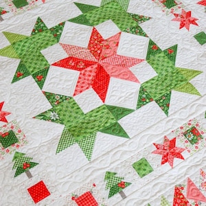 May include: A white quilt with a repeating pattern of red and green stars, trees, and geometric shapes. The quilt features intricate stitching and a festive holiday theme. The quilt is made of various patterned fabrics.