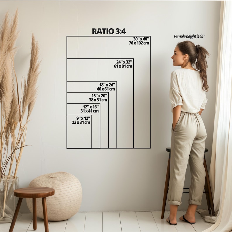 K&ouml;nnte beinhalten: Eine wei&szlig;e Wand mit einer Reihe schwarzer Rechtecke, die verschiedene Gr&ouml;&szlig;en von Leinwanddrucken in Zoll und Zentimetern zeigen. Der Text "RATIO 3:4" befindet sich oben im Bild. Eine Frau steht rechts neben den Rechtecken, und ein kleiner Holzhocker steht vor ihr.