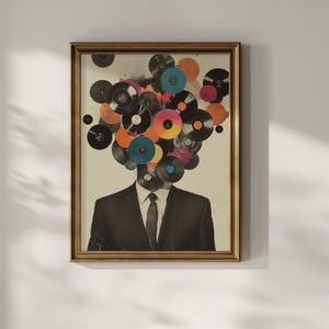 May include: Framed art print featuring a man in a suit with a head composed of colorful vinyl records. The records are various colors, including black, orange, pink, and blue. The artwork is in a gold-colored frame.