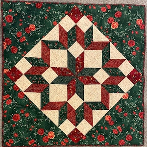 May include: A red, green, and cream quilt with a starburst pattern. The quilt is made of fabric with a floral print.
