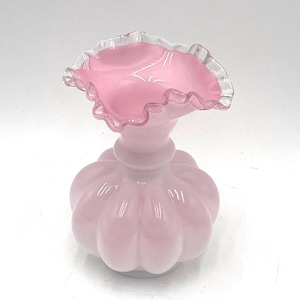 Può includere: Un vaso di vetro rosa con un bordo superiore arricciato e un corpo testurizzato a forma di zucca.