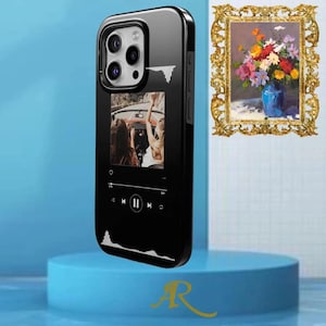 May include: Black phone case with a glossy finish. The case features a music player interface with a photo of people in a car. The case has a black border and a camera cutout. A gold-colored letter "R" is visible.