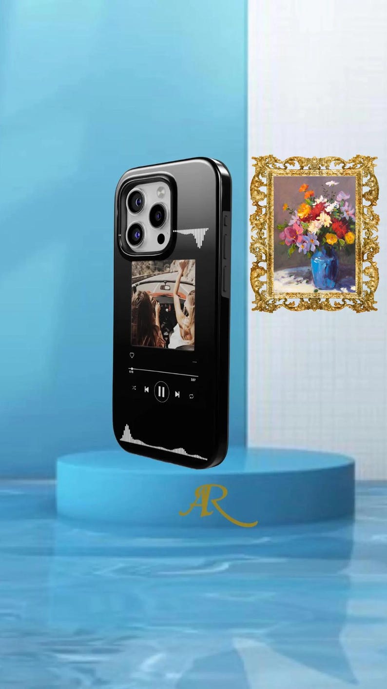 May include: Black phone case with a glossy finish. The case features a music player interface with a photo of people in a car. The case has a black border and a camera cutout. A gold-colored letter "R" is visible.