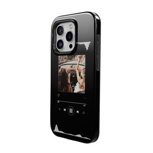 May include: Black iPhone case with a glossy finish. The case features a photo of two people in a car with their arms raised. A music player interface is displayed below the photo, with a waveform graphic at the top and bottom.