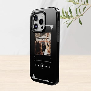 May include: Black phone case with a glossy finish. The case features a photo of two people in a car, with a music player interface design. White sound wave graphics are on the case.