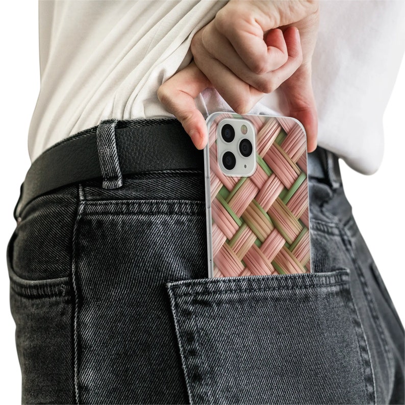 Puede incluir: Una funda transparente para tel&eacute;fono con un patr&oacute;n tejido en tonos rosas y verdes. La funda est&aacute; en un bolsillo trasero de unos vaqueros negros. La funda del tel&eacute;fono tiene una c&aacute;mara con tres lentes.