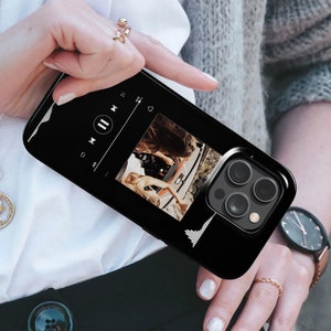May include: Black smartphone case featuring a music player interface with a photo of two people in a car. The case has a glossy finish and a camera cutout. The design includes a waveform graphic on the sides.