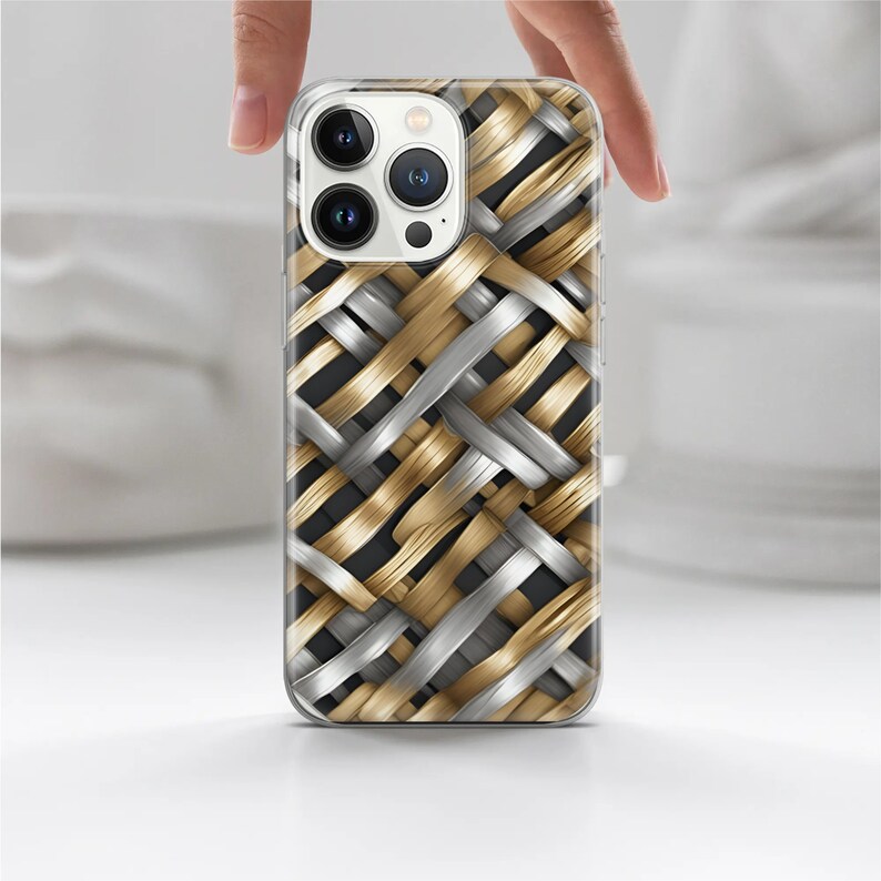 Puede incluir: Funda de tel&eacute;fono inteligente con un patr&oacute;n tejido en colores oro y plata. La funda tiene un borde transparente y est&aacute; sujeta por una mano. El dise&ntilde;o tejido crea una apariencia texturizada.