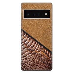 Puede incluir: Una funda de tel&eacute;fono marr&oacute;n con un dise&ntilde;o de cuero texturizado. La parte superior tiene un aspecto de cuero agrietado marr&oacute;n claro, mientras que la parte inferior presenta un patr&oacute;n m&aacute;s oscuro, similar al de un reptil. Una barra de c&aacute;mara negra es visible.