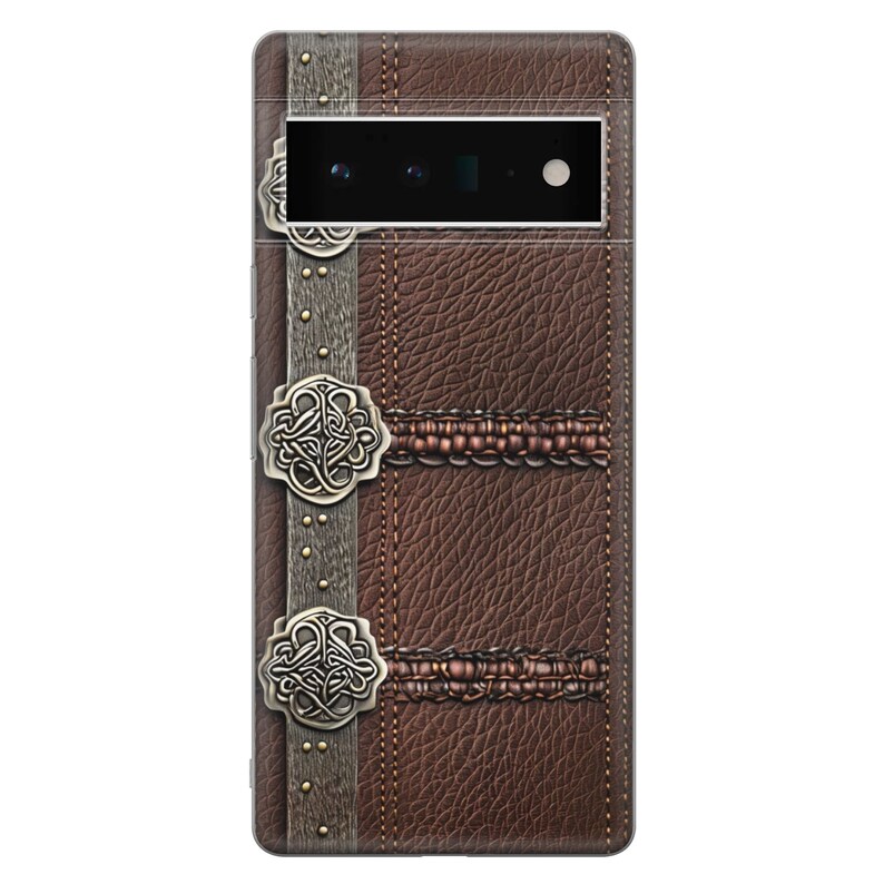 Puede incluir: Una funda de tel&eacute;fono de cuero marr&oacute;n con una superficie texturizada, detalles met&aacute;licos decorativos y un dise&ntilde;o cosido. La funda tiene una apariencia vintage, similar a un libro, con un recorte para la c&aacute;mara en la parte superior.