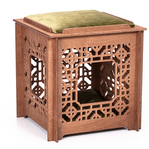 Pode incluir: Uma cama de gato de madeira com uma almofada verde. A cama tem um design de treliça decorativo e é feita de madeira natural.