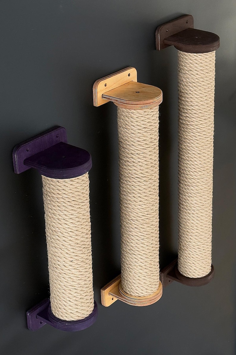 May include: Three cat scratching posts with a natural rope texture and wooden platforms. The platforms are in purple, light brown, and dark brown. The posts are mounted on a dark gray wall.
