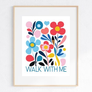 May include: A framed art print featuring a colorful floral design with the words "WALK WITH ME" in teal. The flowers are in shades of red, blue, pink, and yellow, creating a cheerful and vibrant composition. The print is in a light wood frame.