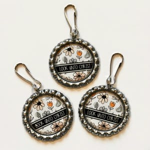 May include: Three silver zipper pulls with floral designs and the text "Look unto Christ" on each.