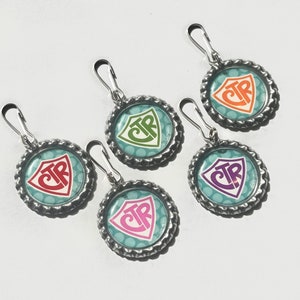 May include: Five zipper pulls with a teal blue background and white polka dots. Each pull has a shield-shaped design with the letters "CTR" in different colors: red, orange, green, purple, and pink.
