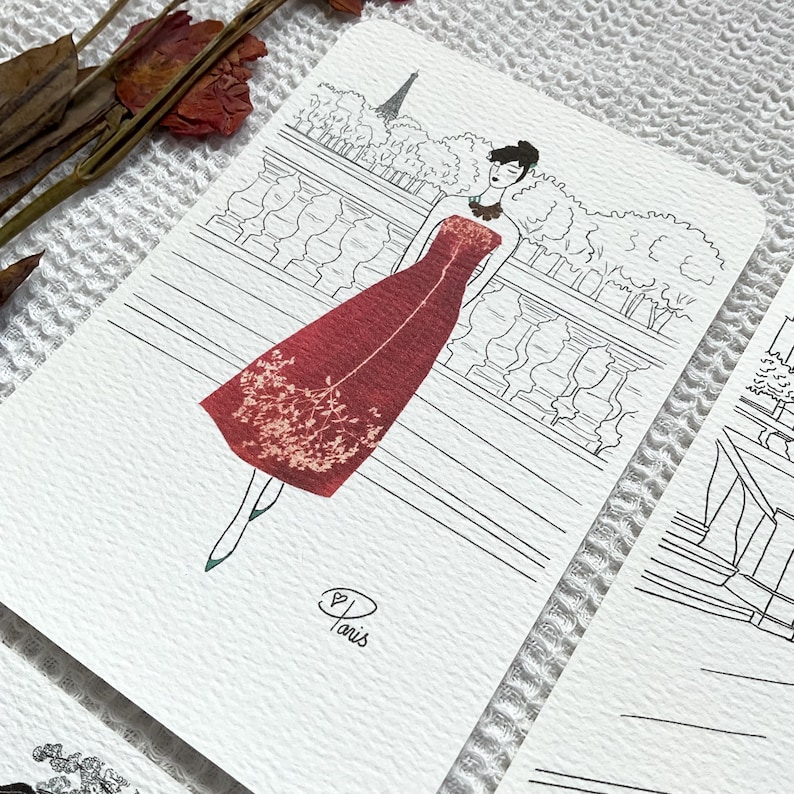 May include: A black and white line drawing of a woman in a red dress standing in front of a Parisian cityscape. The dress is decorated with dried flowers. The text "Paris" is written in cursive at the bottom of the image.