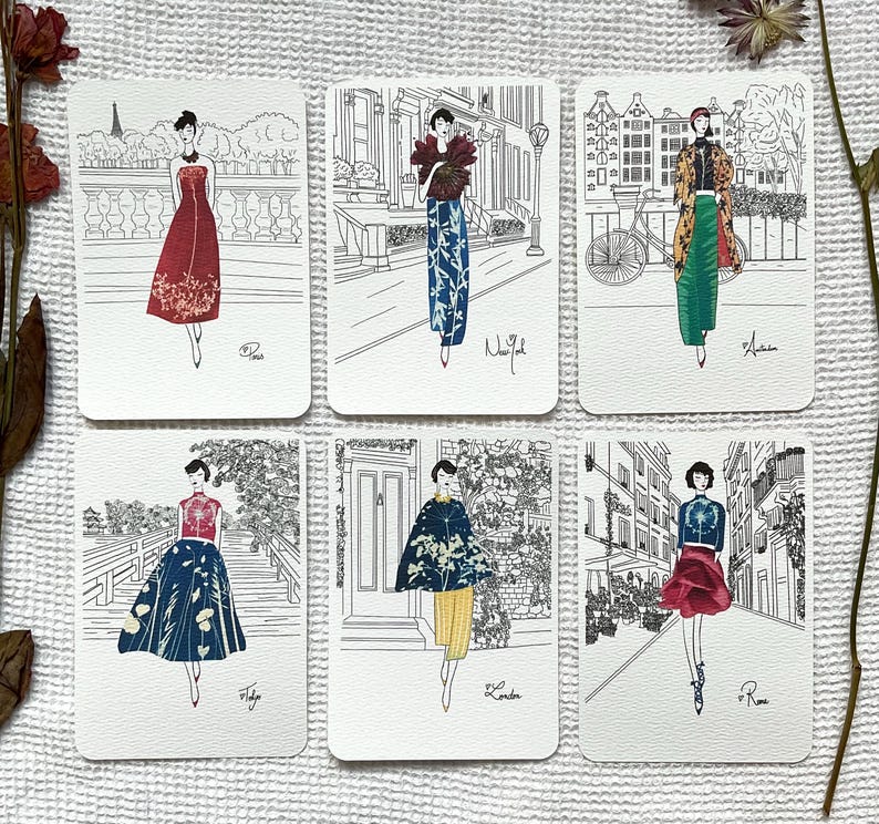 May include: Six illustrated postcards featuring women in different styles of clothing. Each postcard has a city name at the bottom, including Paris, New York, London, and Rome.