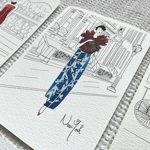 May include: A black and white illustration of a woman in a blue and white patterned dress holding a red flower. The woman is standing in front of a building with the text "New York" written below her.