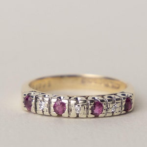 Op de afbeelding: Een gouden ring met een rij van afwisselende robijn- en diamantstenen.