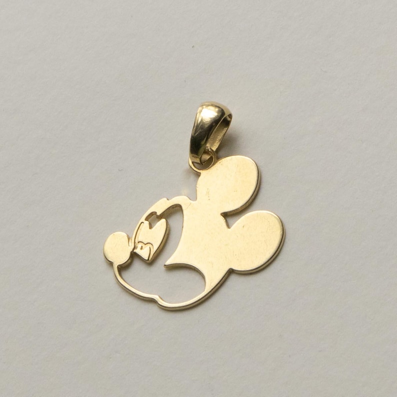 K&ouml;nnte beinhalten: Goldfarbener Anh&auml;nger in Form einer Zeichentrickfigur. Der Anh&auml;nger hat eine Schlaufe f&uuml;r eine Kette und ein stilisiertes Design einer ber&uuml;hmten Maus.