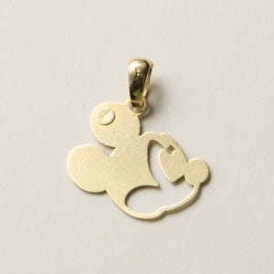 K&ouml;nnte beinhalten: Goldfarbener Anh&auml;nger in Form einer Zeichentrickfigur. Der Anh&auml;nger hat oben eine Schlaufe f&uuml;r eine Kette und ein stilisiertes Design mit abgerundeten Formen und einem kleinen Kreis.