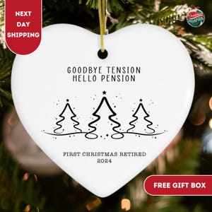 May include: White heart-shaped Christmas bauble with black text that reads "Goodbye Tension Hello Pension" and "First Christmas Retired 2024". The bauble features a stylised design of three Christmas trees.